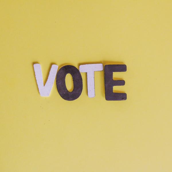 the letters vote arranged on a yellow background