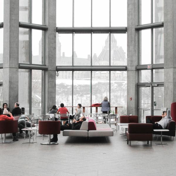 people in a lounge area in a foyer with large windows