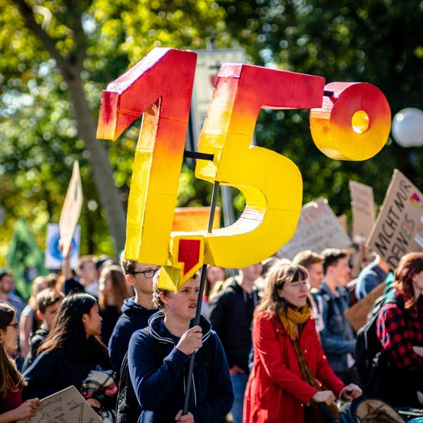 a crowd holding a sign saying 1.5 degrees